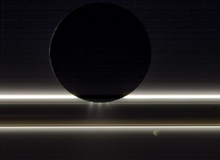A black and white image of Saturn as well as its moons Enceladus and Pandora.