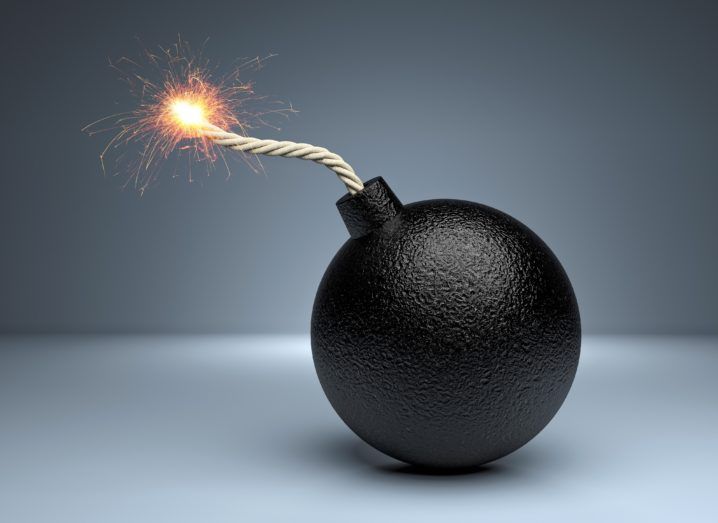 An old-fashioned bomb with a lit fuse on a grey background.
