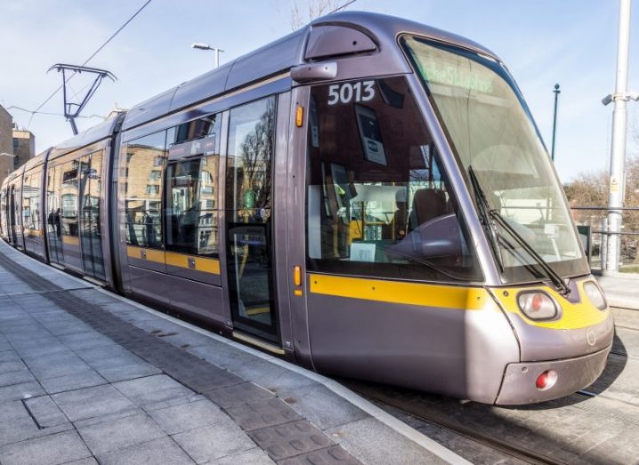 A Luas tram moving on the tracks with a blue sky in the background.