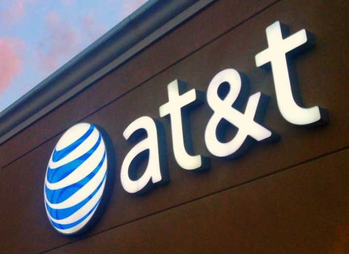 The ATT logo on the side of an office building, with a blue sky with pink clouds in the background.