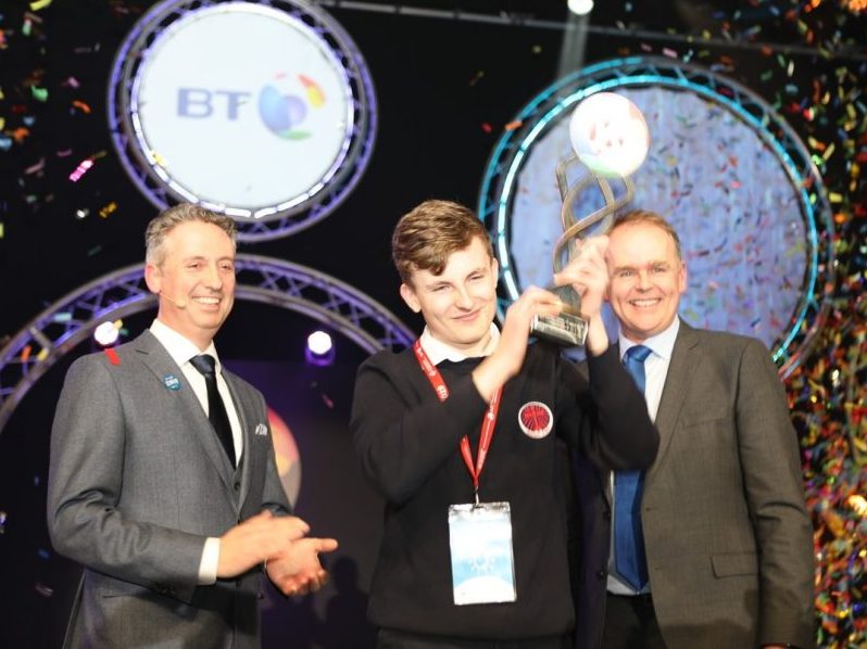 BT Young Scientist winner Adam Kelly holds his trophy aloft as confetti pours down on him.