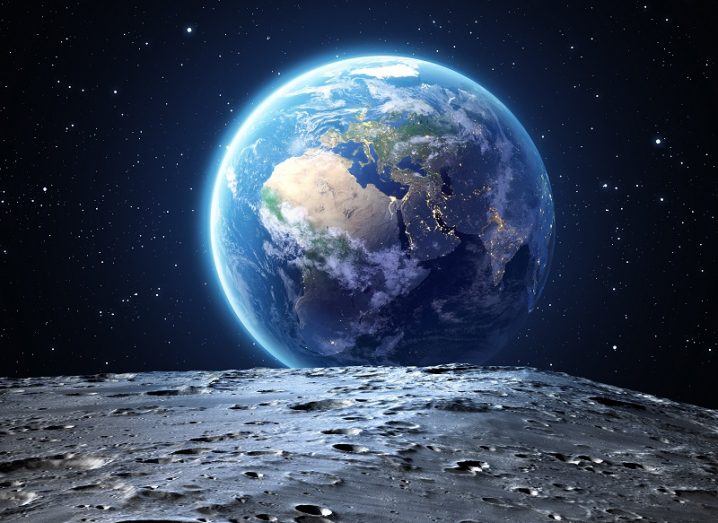 Illustration of the moon surface in the foreground and the Earth overshadowing it in the background.