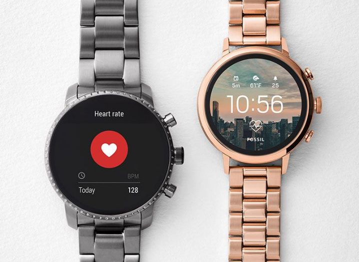 Two Fossil smartwatches. Grey metal on left with rose gold model on right, displays featuring heart rate monitors.