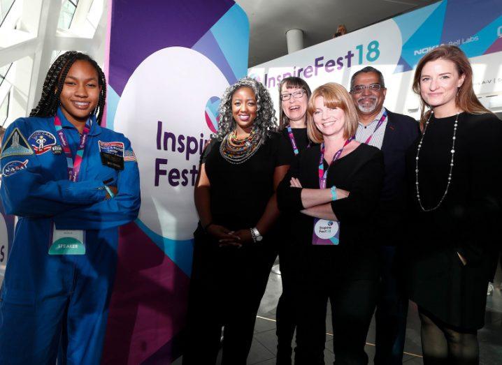 A young girl in a space camp jumpsuit, four women and an older man pose for a group photo at Inspirefest 2018.