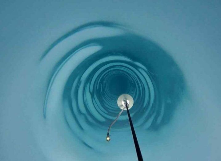 A shot inside the blue and white ice hole with a length of cable reaching down into it.