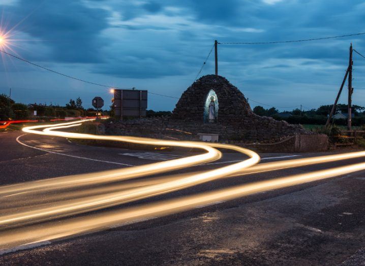 Traffic lights swirl around a religious statue on outskirts of an Irish town.