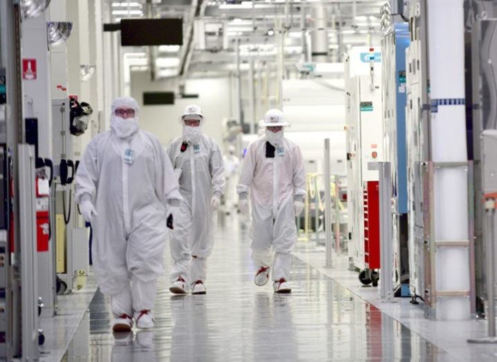 Intel workers in white clean room suits at a wafer fabrication facility.