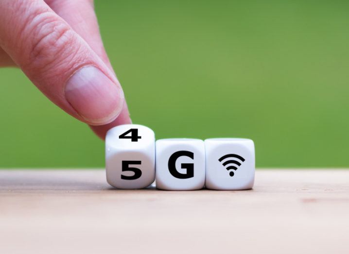 Picture of a hand turning dice with 4G and 5G wireless symbols against a green background.