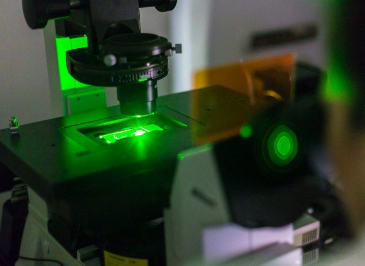 Close-up of a genetic microscope with a green laser shining on the sample.
