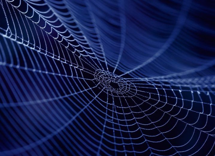 A close-up image of a spider web at night time.