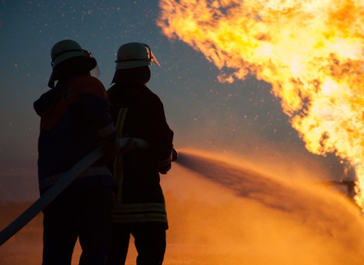 Silhouette of firefighters battling a raging blaze.