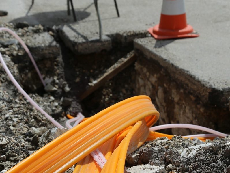 Some roadworks for the installation of fibre broadband, featuring large fibre cable and a traffic cone.