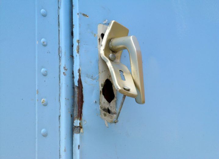 A blue metal door with a broken handle. Data breach concept.