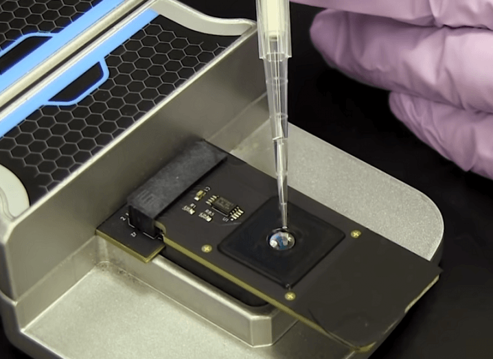 Close-up of a genetic sample being placed on a reader and inserted into the CRISPR-Chip device.