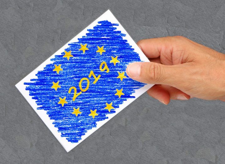 A crayon-drawn image of the EU flag with 2019 in its centre in the hand of a person about to cast a vote.