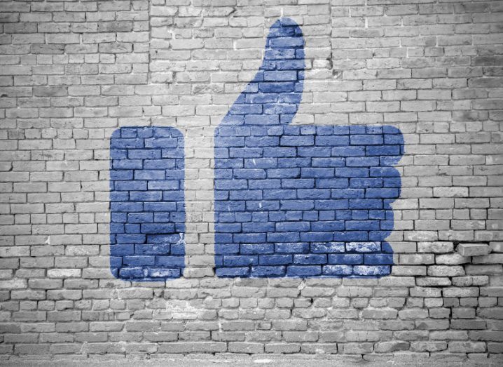 Graffiti of a blue Facebook thumbs-up against a grey wall.