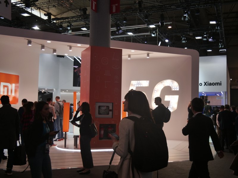 Crowds of people at Mobile World Congress walking past a 5G sign at the Xiaomi stand.