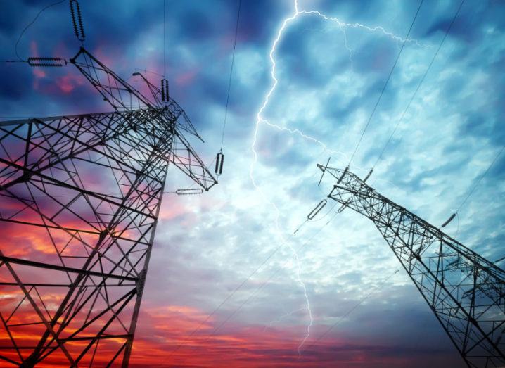 Dramatic image of power distribution station under a blue and red sky with lightning striking.