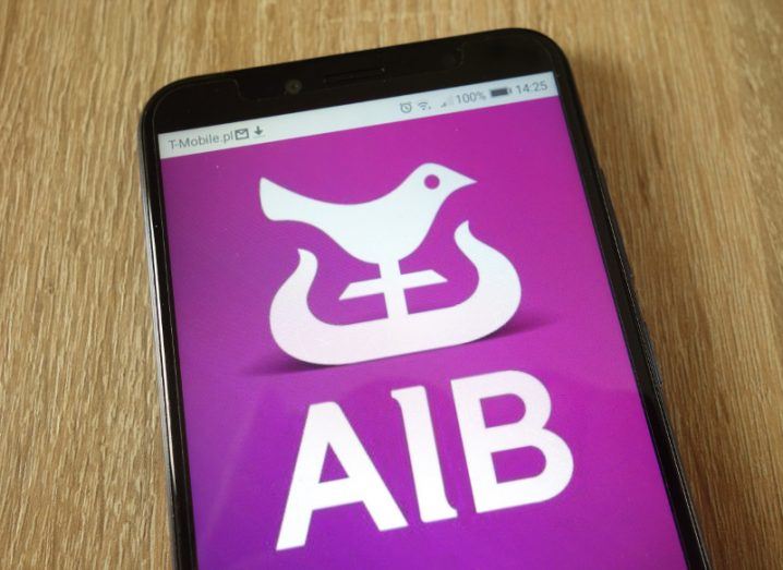 Close-up of AIB banking app on a smartphone on a wooden surface.