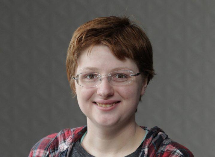 Headshot of Aisling Brennan, a smiling, casually dressed young woman in spectacles.