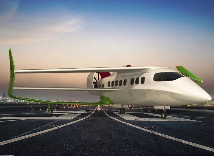A concept shot of the white and green hybrid electric BEHA aircraft with three wings on a runway.