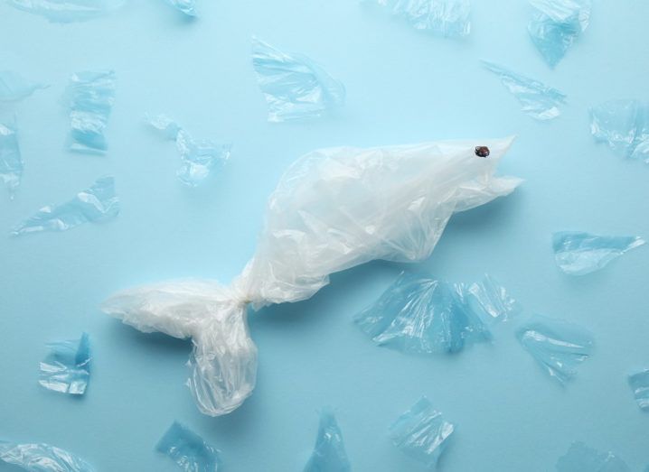 Concept of a white fish made from plastic material surrounded by small, blue plastic fish against a blue background.