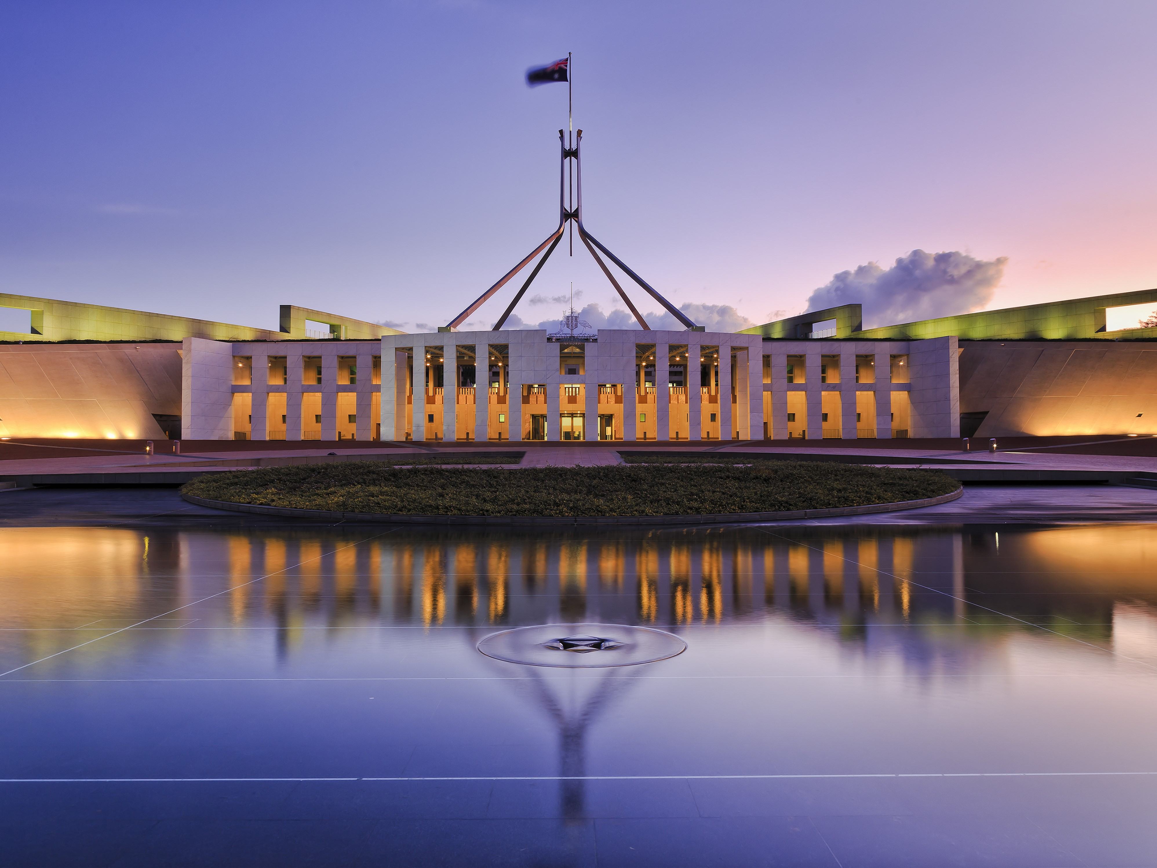 colourful reflection of Canberra's new parliament building in a fountain pond at sunset.