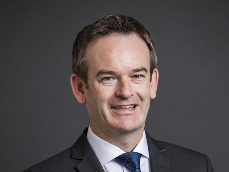 Man in grey suit with blue tie and white shirt.