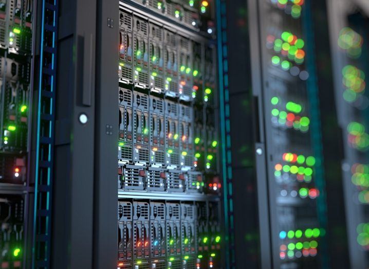 Blurred close-up of green lights on data centre server stacks.
