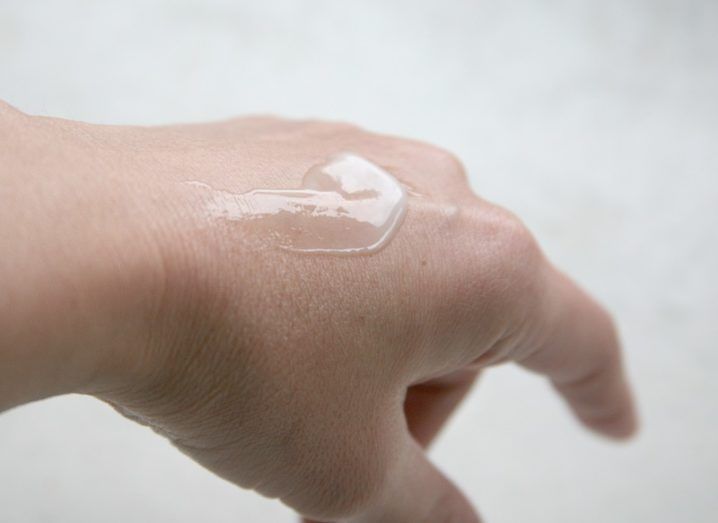 A woman's hand held out with translucent gel on it against a white background.