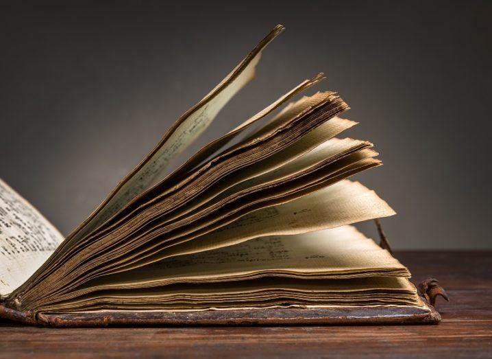 Side profile of an old, open book on a wooden table.