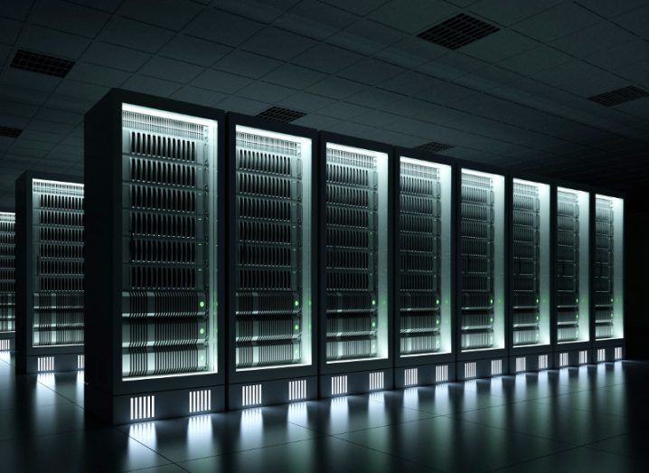 A cluster of servers in a data centre hall emitting a light green light.