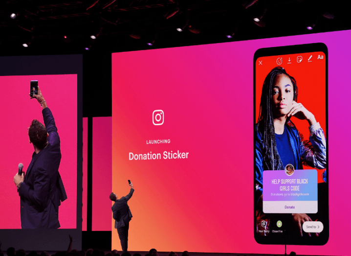 A man takes a picture on stage indicating how a new donation sticker works on Instagram.