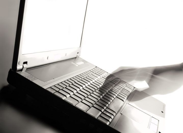 A ghostly hand touches a computer keyboard.