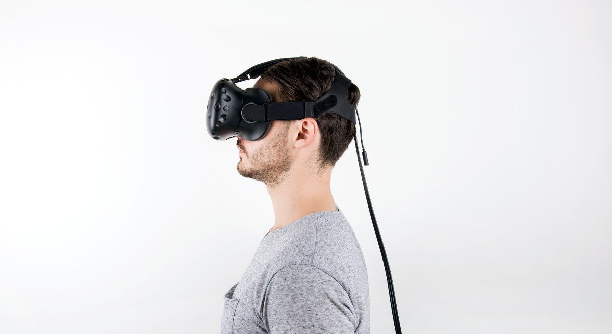 Profile view of a man in a grey T-shirt wearing a virtual reality headset.