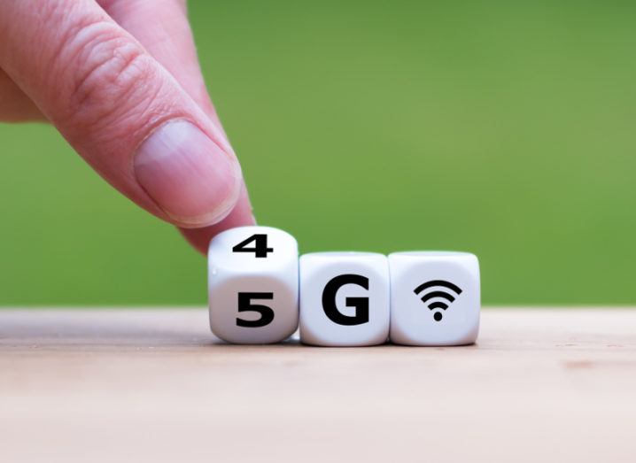 View of dice saying 4G being switched with single finger to say 5G against lime background.