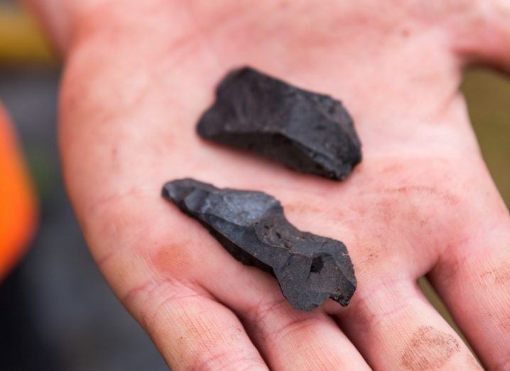 A hand holding two recovered black tool artefacts.