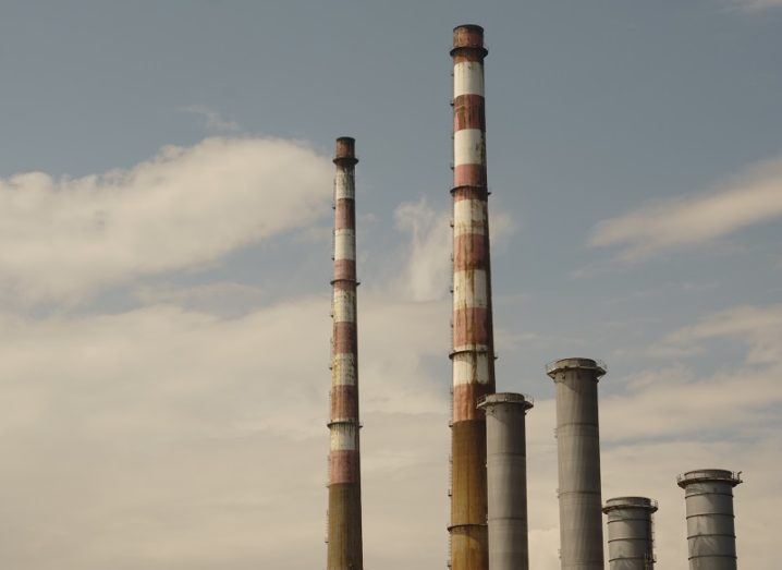 Yellow filter photo of the red and white Poolbeg Power Station chimney stacks against a cloudy background.