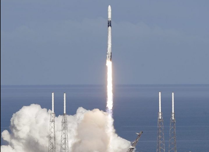 A Falcon 9 SpaceX rocket taking off at Cape Canaveral against a blue sky.