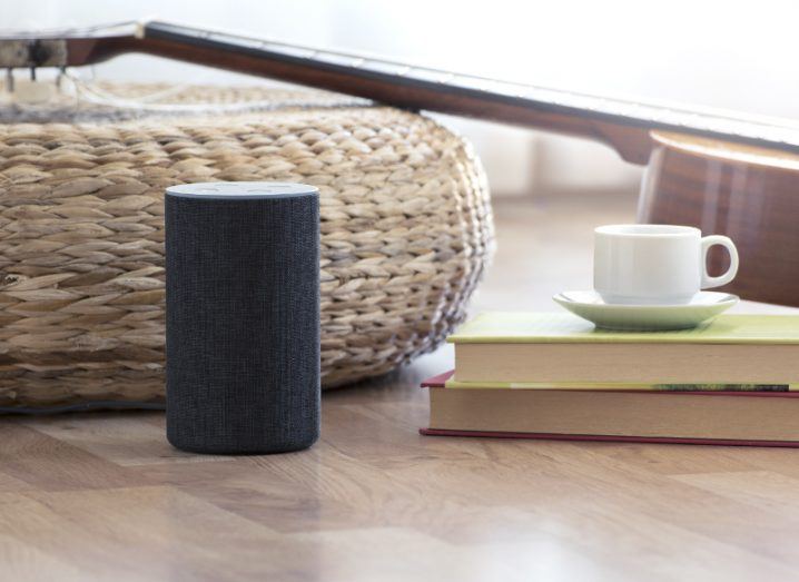 Amazon Alexa personal assistant speaker sitting in living room in front of wicker basket.