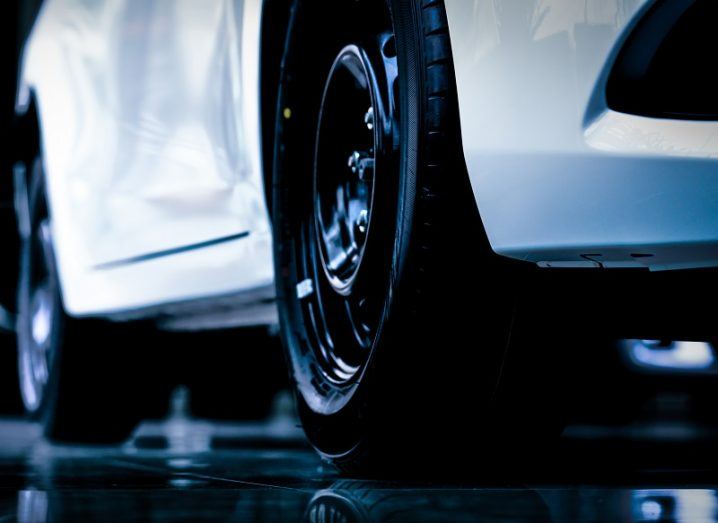 Ground shot of a car tyre fitted to a white sports car.