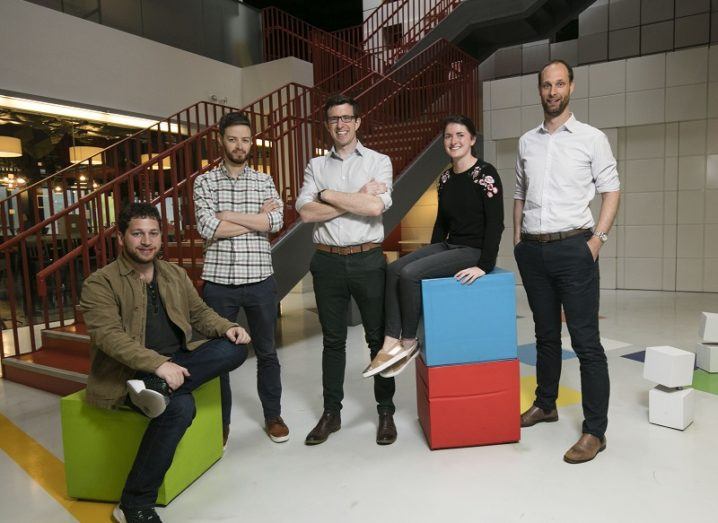 Five members of the EdgeTier team posing for a photo while sitting and standing in Google's offices.