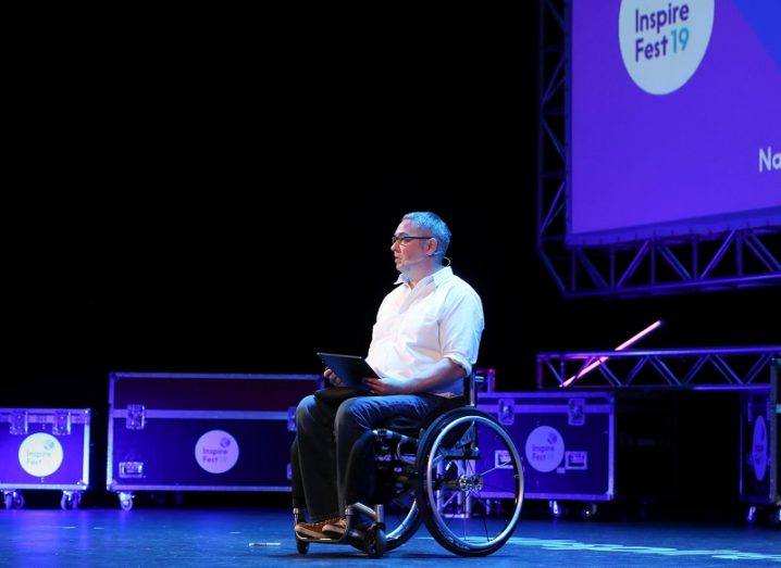 Noel Joyce in a white shirt and black trousers with equipment in the background on stage at Inspirefest 2019.