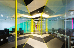 A corridor at the Huckletree offices featuring glass panels and vibrant lighting in yellow