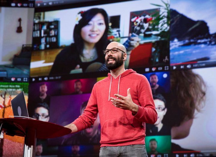 Patreon CEO Jack Conte onstage wearing a red hoodie and grey jeans.