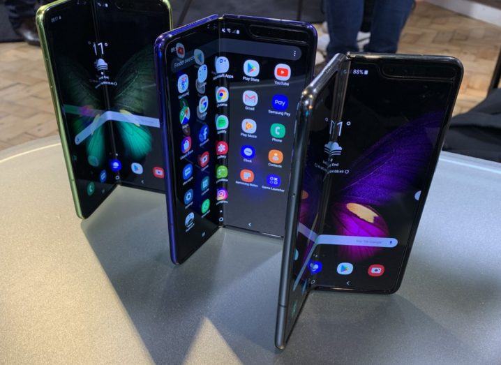 View of three Galaxy Fold smartphones standing on table.