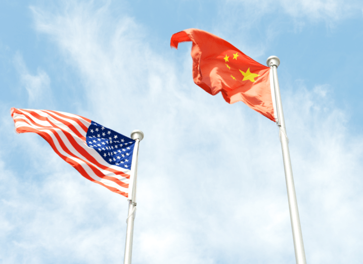 An American flag and a Chinese flag flying at full mast beside each other.