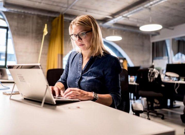 Anja Hendel in a blue shirt working at a laptop at a desk at the Porsche Digital Lab.