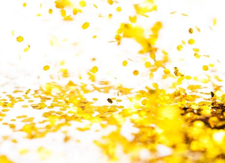 Gold glitter falling to the ground against a white background.