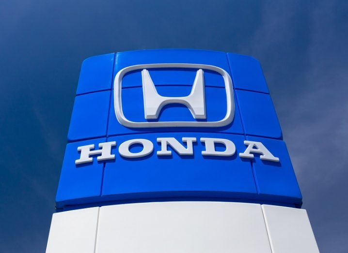 Blue sign with the Honda badge and name on it against a dark blue sky background.